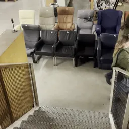 Zwarte leren stoelen en fauteuils in een winkelruimte met grijs linoleum