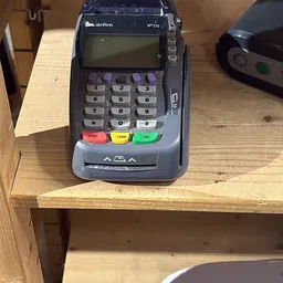 Betaalterminal met nummertoetsen en gekleurde knoppen op een houten plank