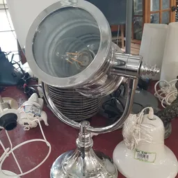 Grote zilverkleurige spotlamp of schijnwerper op standaard met geelgroene glazen lens