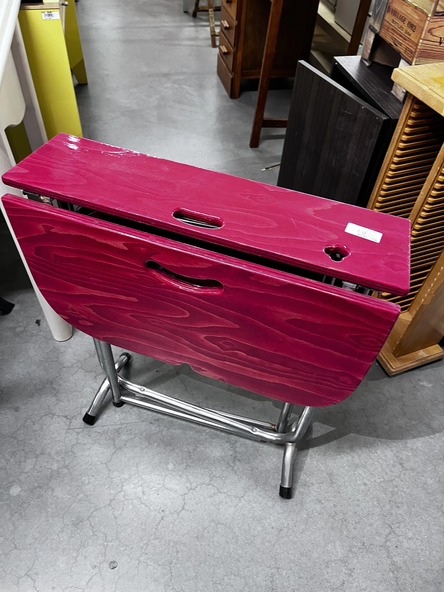 Roze/magenta opvouwbare tafel met zwart metalen onderstel, van bovenaf gefotografeerd