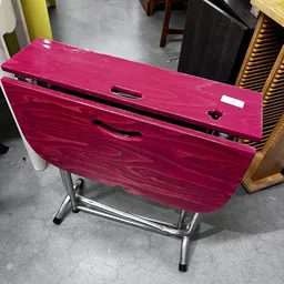 Roze/magenta opvouwbare tafel met zwart metalen onderstel, van bovenaf gefotografeerd