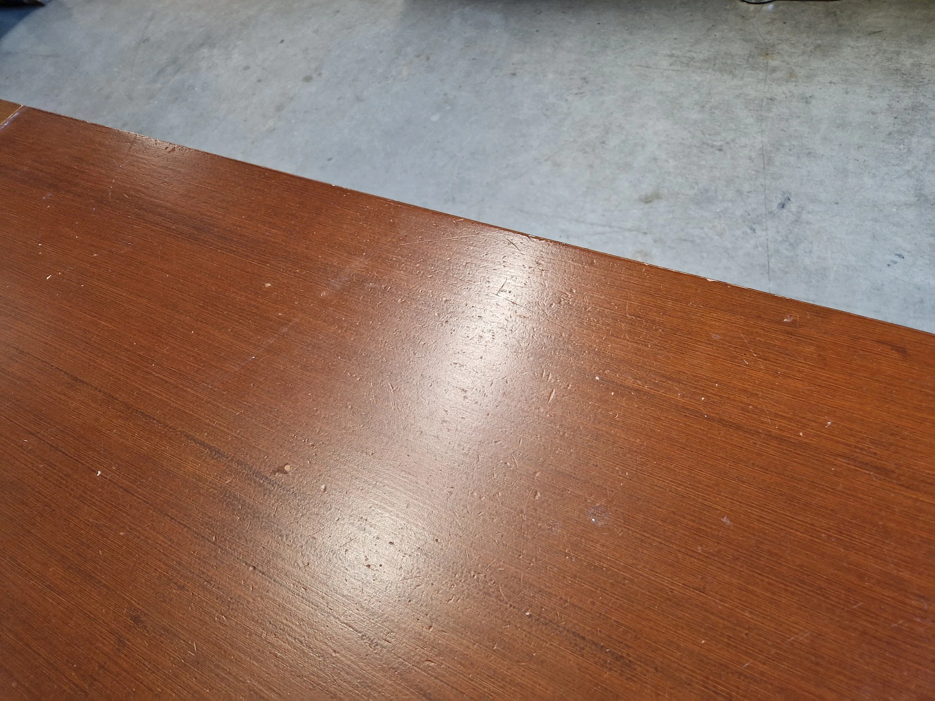 Close-up van een houten tafelblad met glanzende afwerking op betonnen vloer