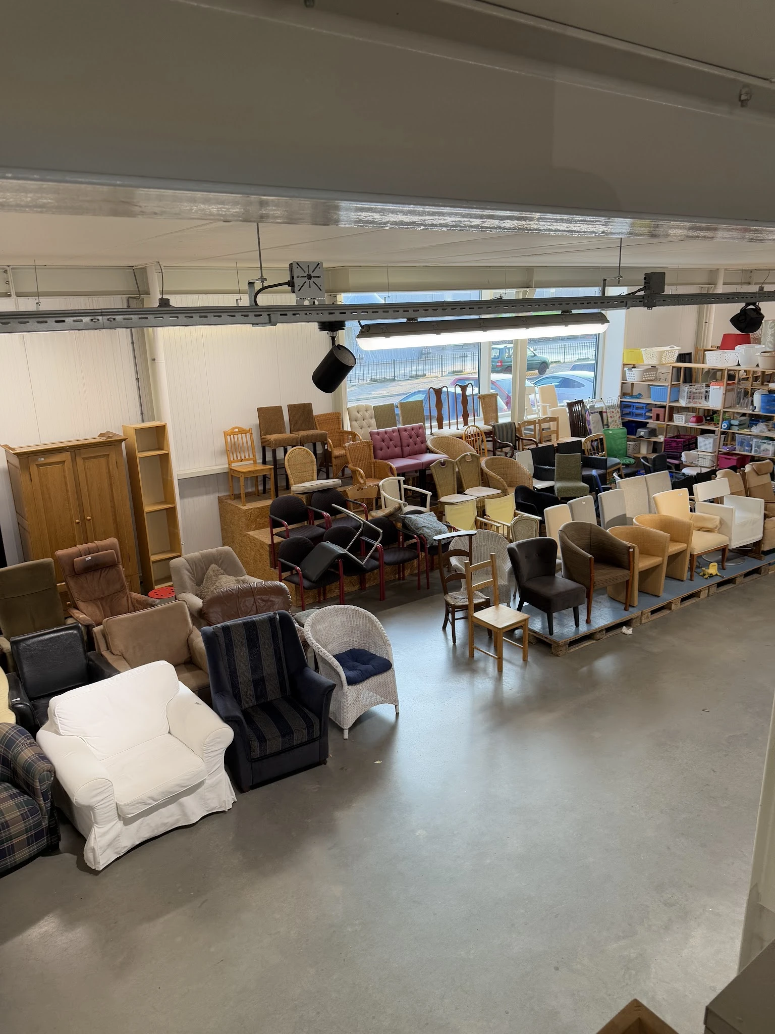 Winkelvloer met diverse tweedehands meubels: stoelen, tafels, kasten en fauteuils uitgestald in de ruimte