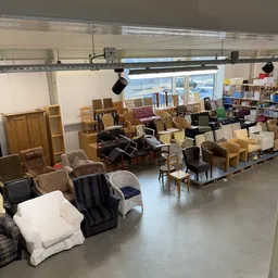 Winkelvloer met diverse tweedehands meubels: stoelen, tafels, kasten en fauteuils uitgestald in de ruimte
