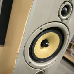 Close-up van een witte luidspreker met geel/crème kleurig cône-element