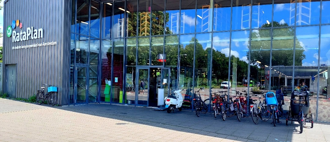 Glazen gevel van kringloopwinkel met fietsen geparkeerd voor de ingang