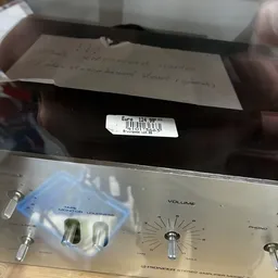 Close-up van een vintage versterker met volumeknop en een prijssticker