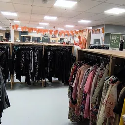 Rekken met tweedehands kleding, zwarte kledingstukken op voorgrond en gekleurde items op achtergrond