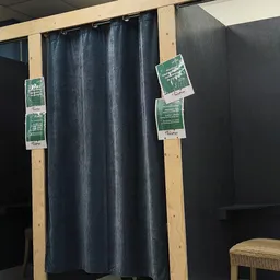 Donkergrijze gordijnen op houten stangen met groene prijskaartjes