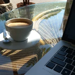 Kopje koffie op een tafel bij een raam met uitzicht, laptop op de achtergrond
