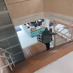 Overzicht van winkelinterieur met turquoise toonbank en bezoeker op trap