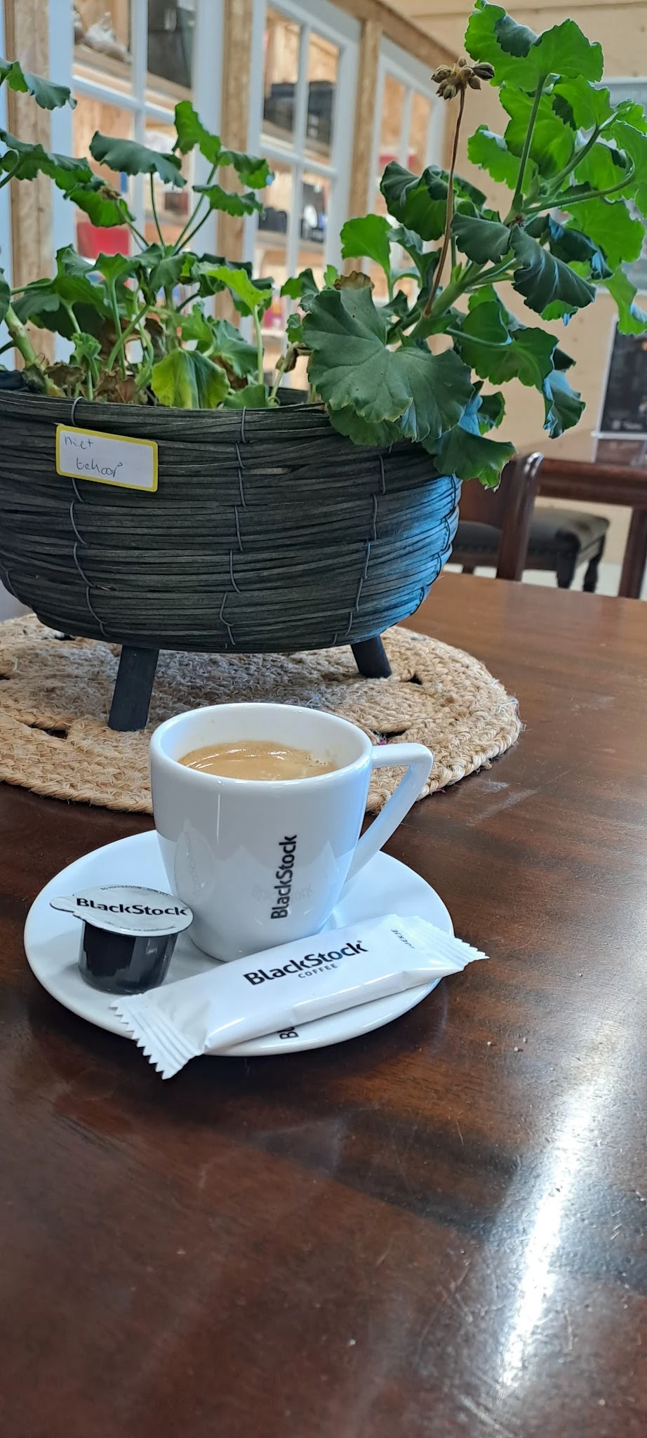 Kopje koffie met BlackStock-logo op schotel met decoratieve objecten op achtergrond