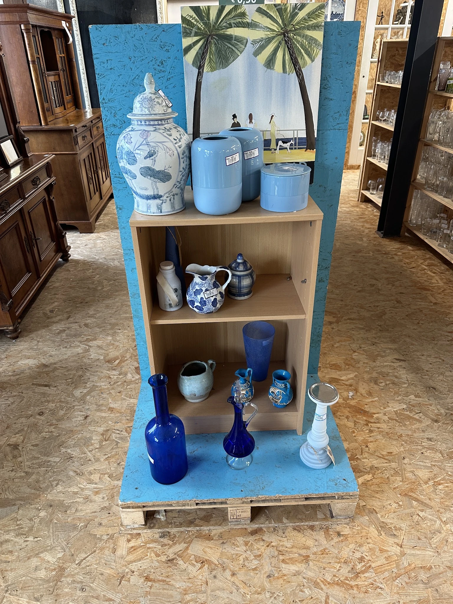 Stellingkast met blauw en wit serviesgoed, kannen, flessen en decoratieve items