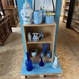 Stellingkast met blauw en wit serviesgoed, kannen, flessen en decoratieve items