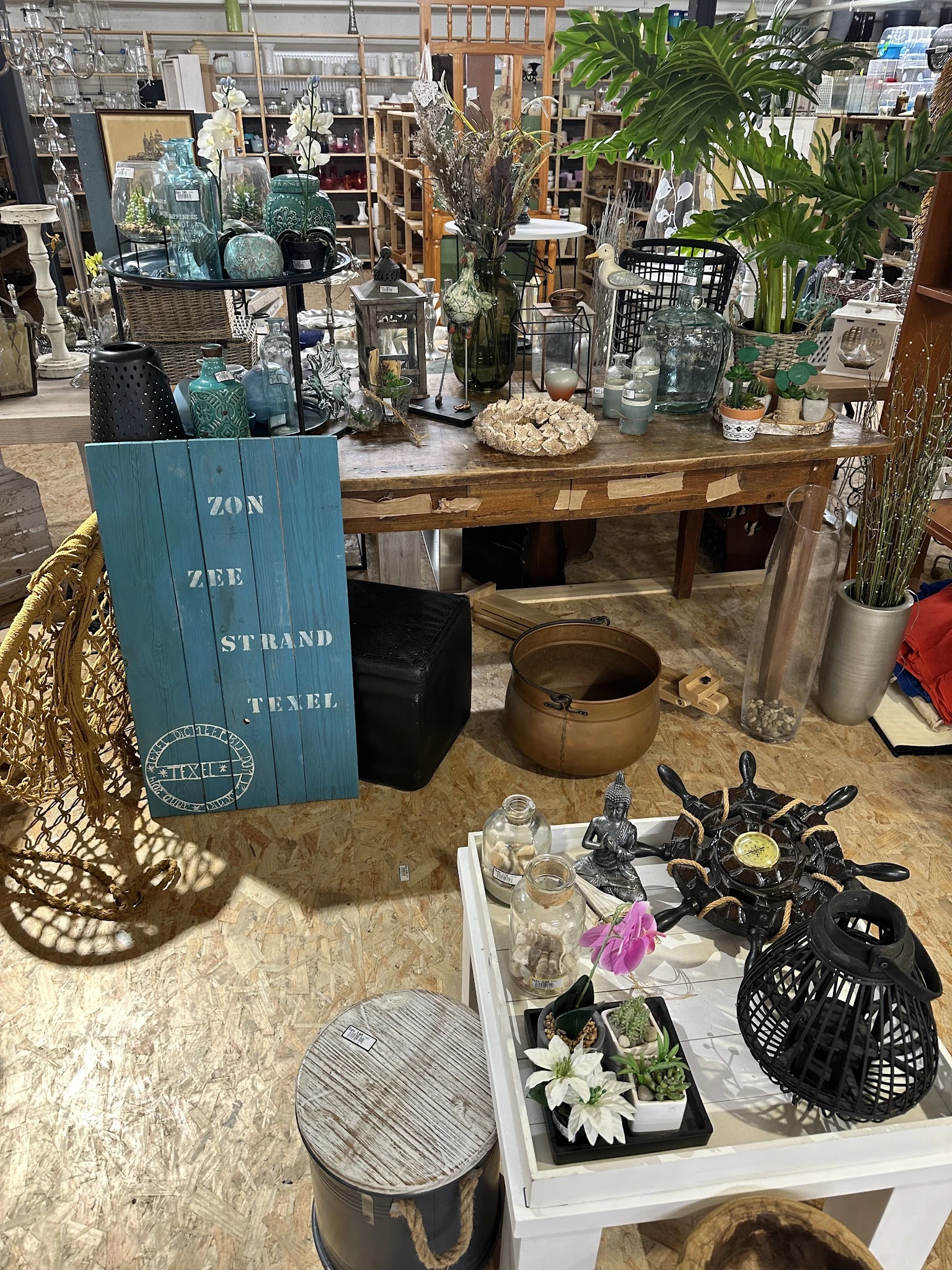 Uitgestalde tweedehands huishoudartikelen en decoratie op tafel en plank in de winkel