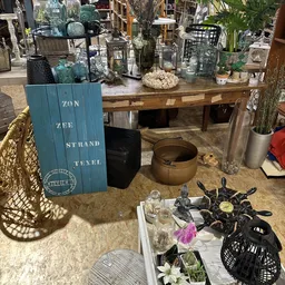 Uitgestalde tweedehands huishoudartikelen en decoratie op tafel en plank in de winkel