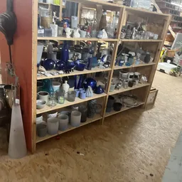 Houten stellingen met huishoudelijke artikelen en serviesgoed in verschillende kleuren