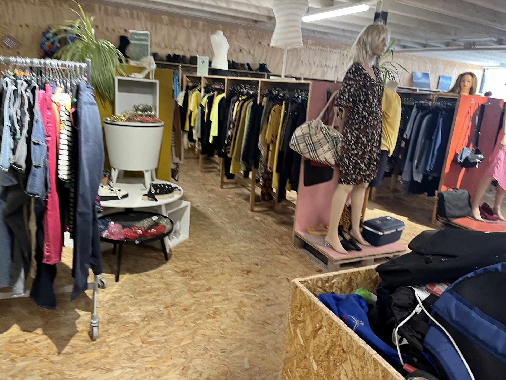 Winkelvloer met kledingrekken en uitgestalde tweedehands kleding in verschillende kleuren