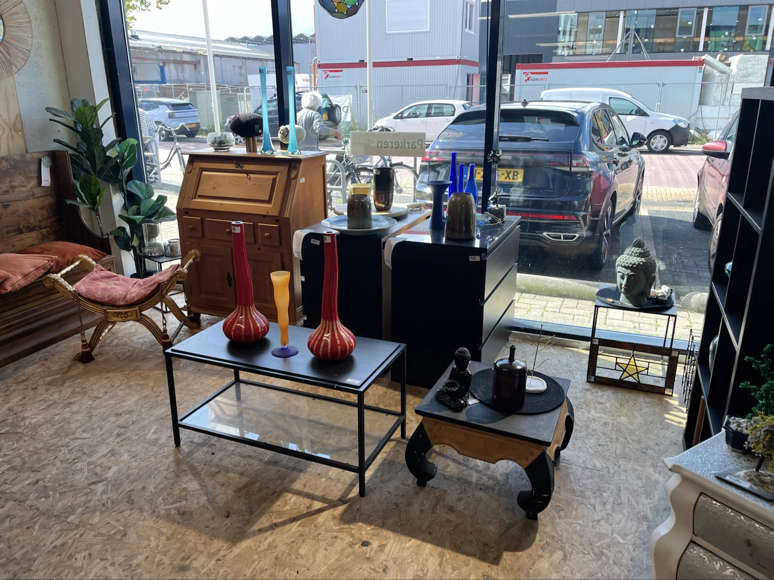 Winkelinterieur met zitmeubels, decoratieve objecten en ramen met uitzicht op parkeerterrein