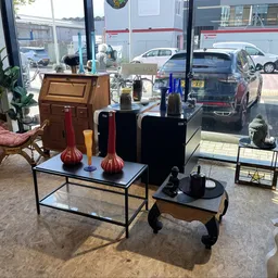 Winkelinterieur met zitmeubels, decoratieve objecten en ramen met uitzicht op parkeerterrein
