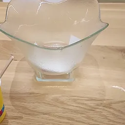 Glazen mengkom met witte inhoud op houten werkblad