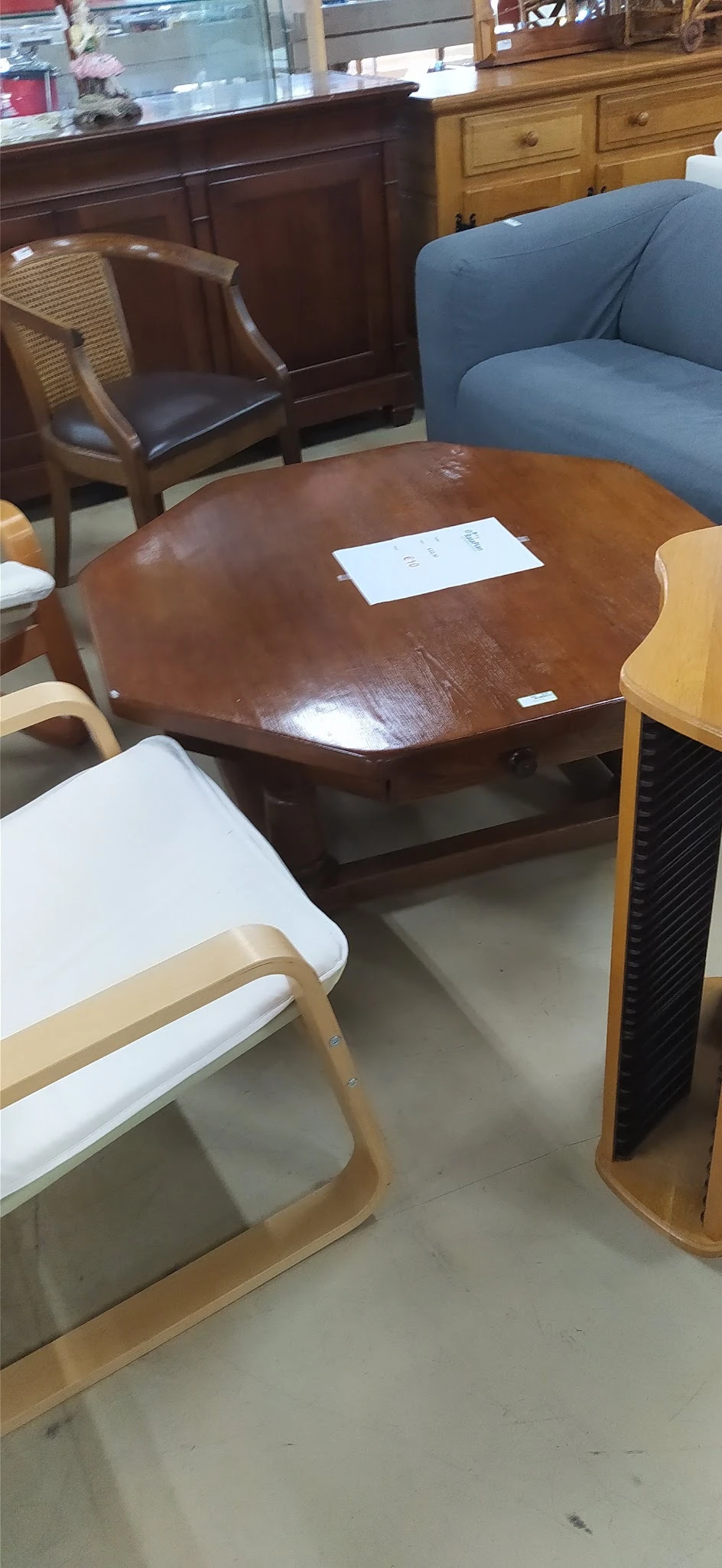 Bruine houten eettafel met blad en onderblad, met witte stoelen ernaast