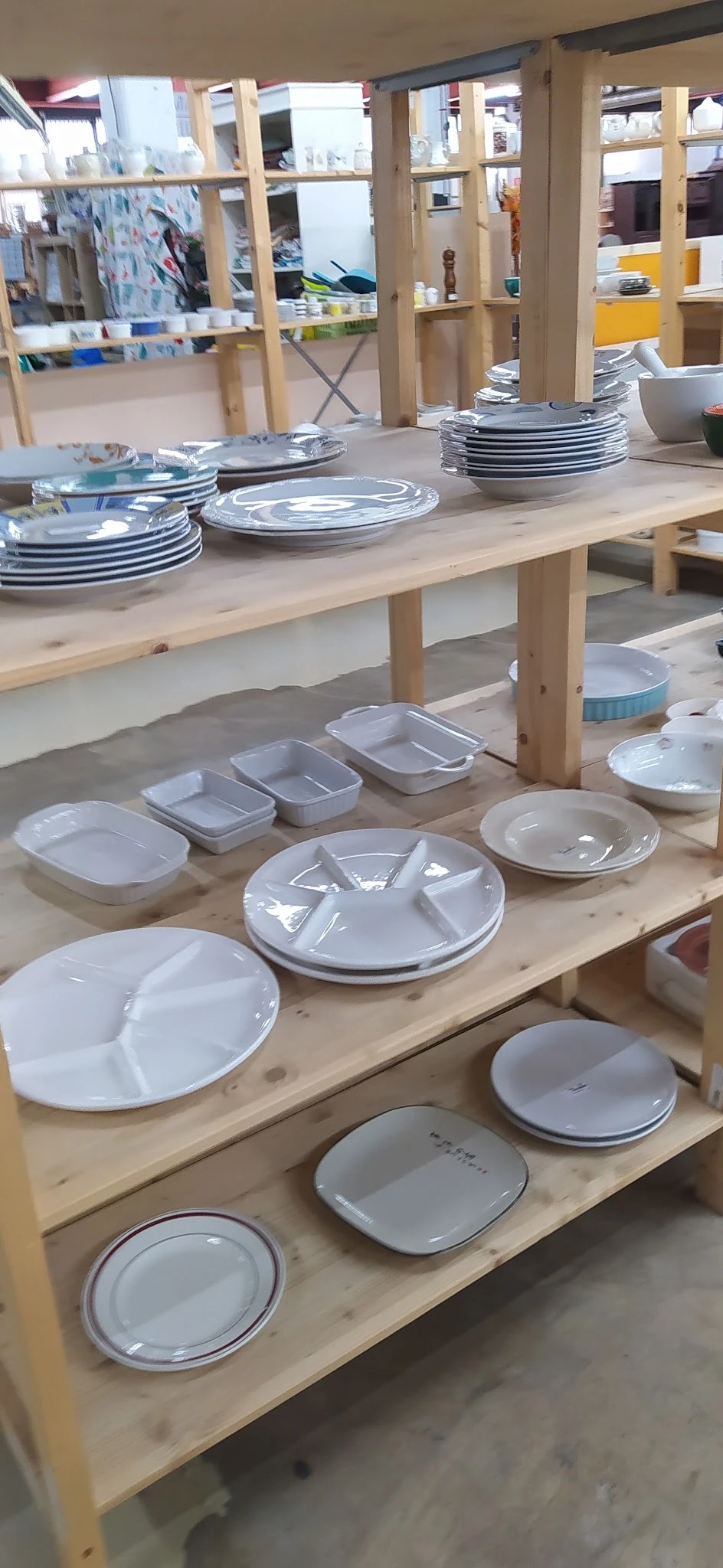 Diverse witte serviesgoed zoals schalen, borden en compartimentenschalen uitgestald op houten tafels
