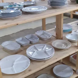 Diverse witte serviesgoed zoals schalen, borden en compartimentenschalen uitgestald op houten tafels