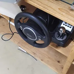 Zwart gaming stuurwiel met pedalen en versnellingsbak op houten plank