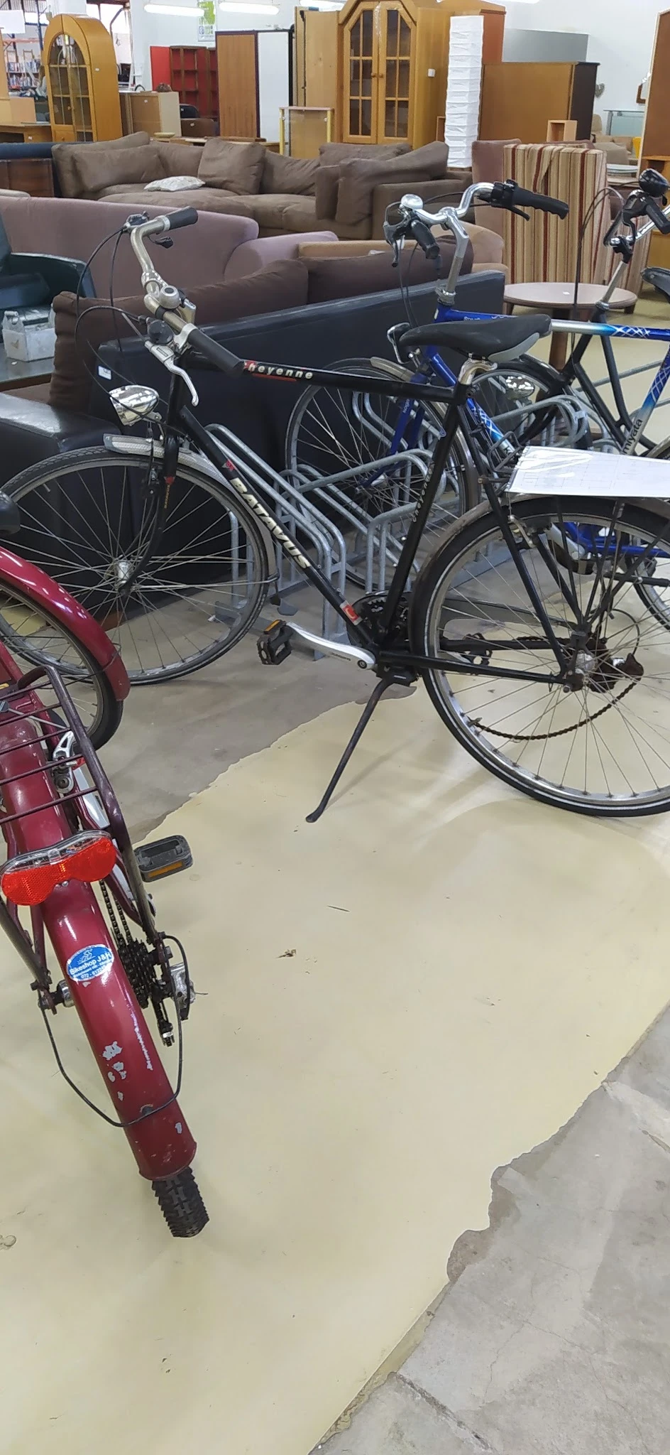 Tweedehands fietsen op de grond, waaronder een zwarte en een rode fiets