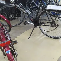 Tweedehands fietsen op de grond, waaronder een zwarte en een rode fiets