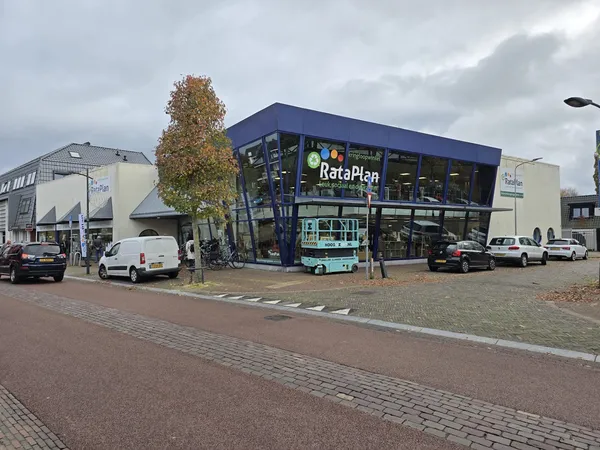 Voorgevel van RataPlan kringloopwinkel met blauwe gevel en grote raampartijen aan dorpsplein