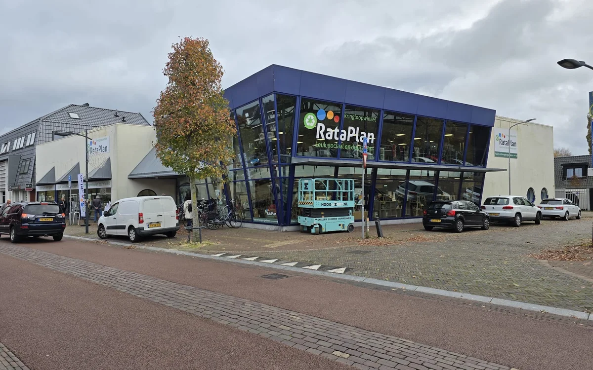 Voorgevel van RataPlan kringloopwinkel met blauwe gevel en grote raampartijen aan dorpsplein