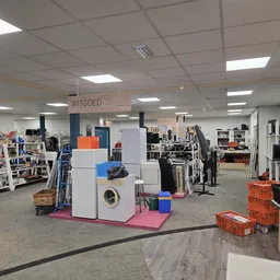Winkelruimte met verschillende afdelingen, stellingen met spullen en een display met huishoudapparatuur in het midden