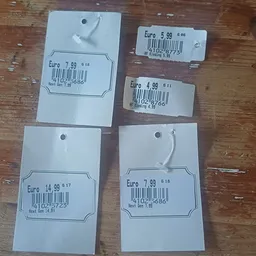 Vijf prijskaartjes met Euro-bedragen en barcodes op houten ondergrond