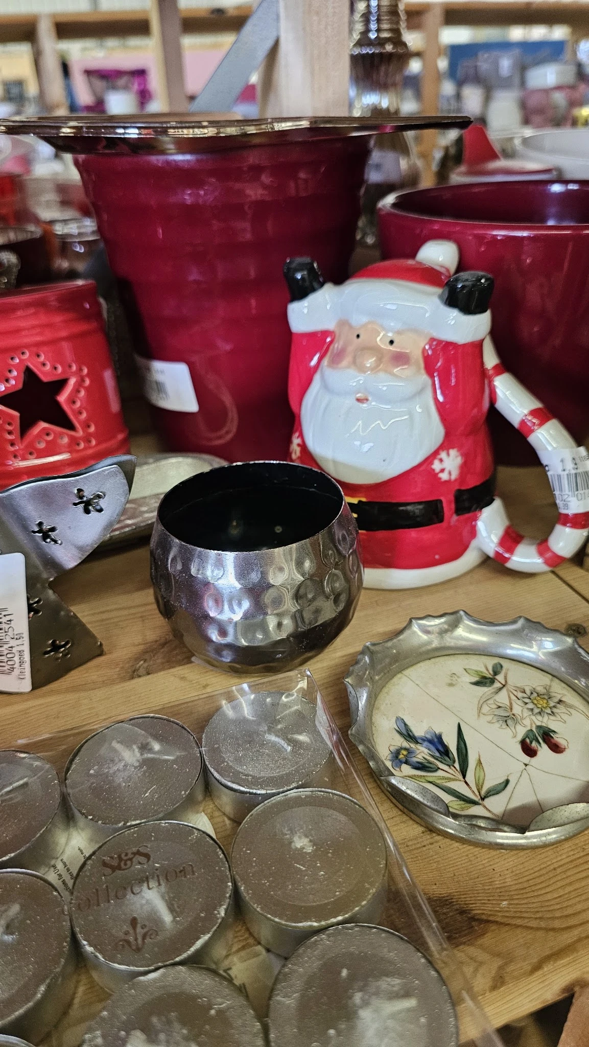 Kerstaccessoires en decoratieve items op een houten tafel, waaronder een zwarte pot en rode kerstmanfiguren