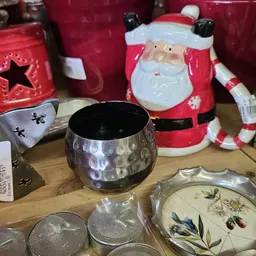 Kerstaccessoires en decoratieve items op een houten tafel, waaronder een zwarte pot en rode kerstmanfiguren