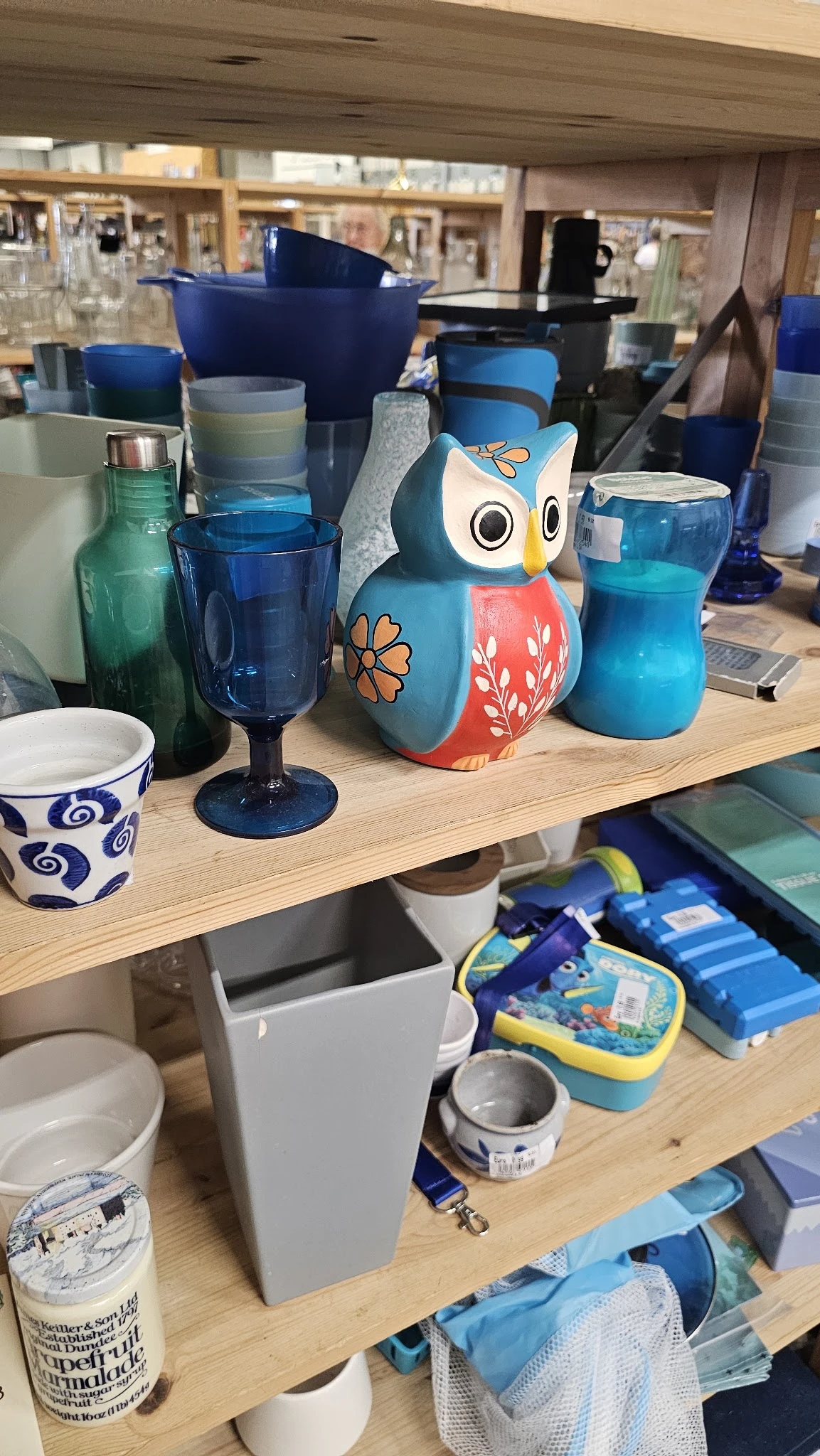 Tafel met diverse items: blauwe glazen, een decoratieve uil, flessen en kopjes met blauwe patronen.