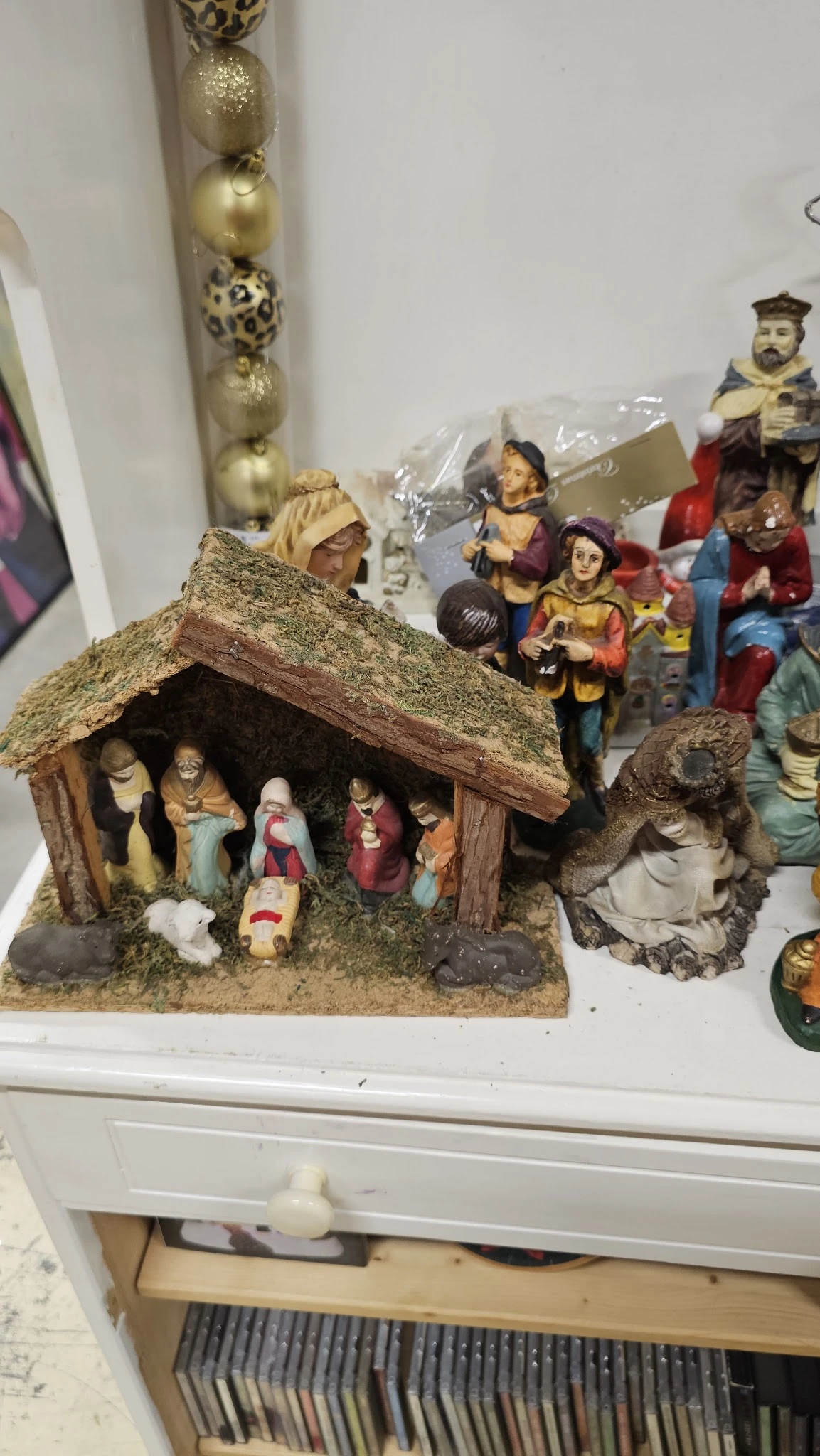 Kerststalletje met houten dak en figuren van Maria, Jozef en kind Jezus, naast decoratiefiguren