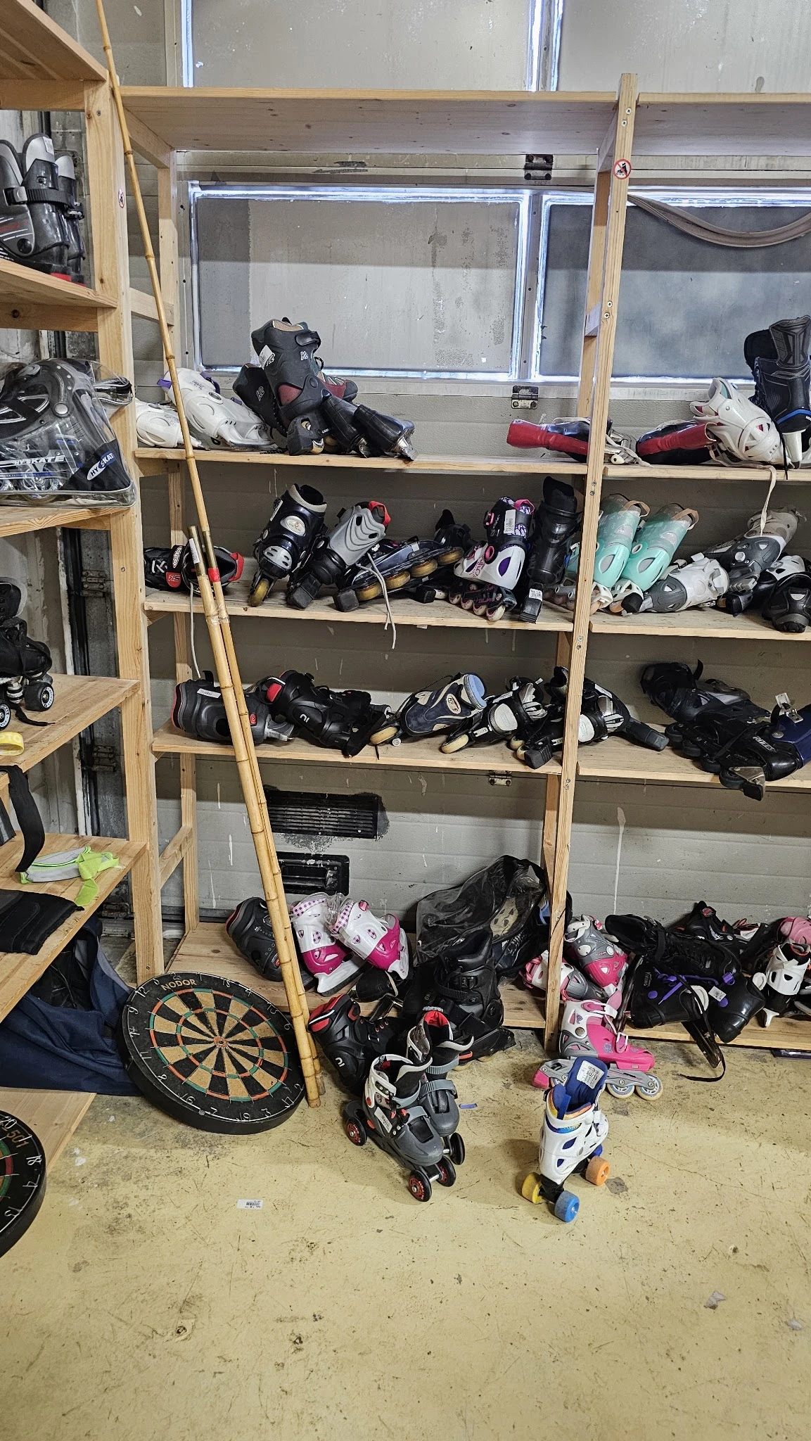 Houten stellingen vol met tweedehands sportuitrusting en beschermingsmateriaal, waaronder helmen, pads en skates