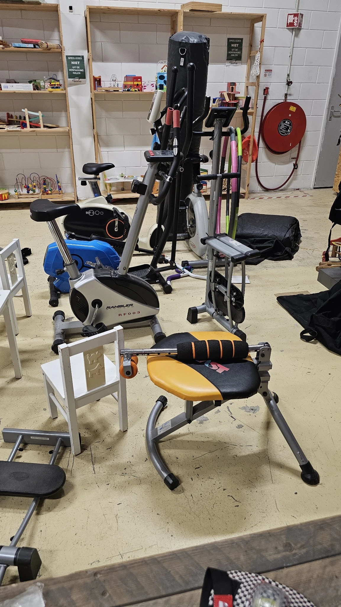 Verschillende tweedehands fitnessapparaten uitgestald in de winkel, waaronder hometrainers en trainingsapparatuur