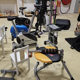 Verschillende tweedehands fitnessapparaten uitgestald in de winkel, waaronder hometrainers en trainingsapparatuur