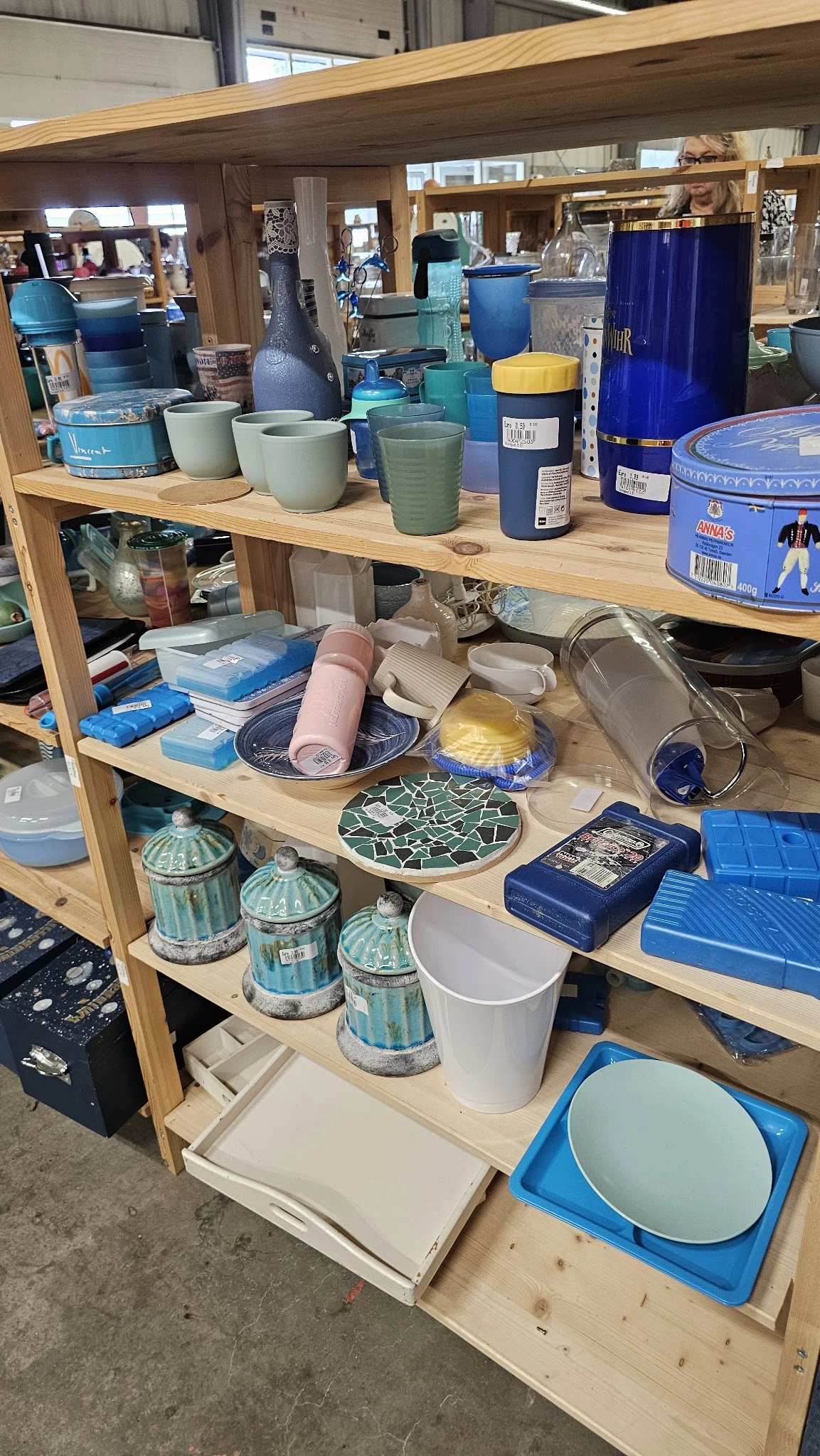 Houten stellingkast met diverse huishoudartikelen: plastic bakjes, serviesgoed, decoratieve schalen en opbergdozen