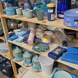Houten stellingkast met diverse huishoudartikelen: plastic bakjes, serviesgoed, decoratieve schalen en opbergdozen