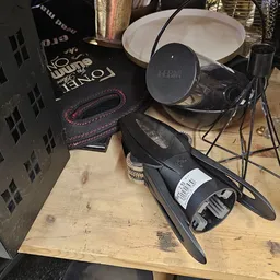 Close-up van een zwarte microfoon met witte label op houten tafel, met boeken en ander audiogereedschap op de achtergrond