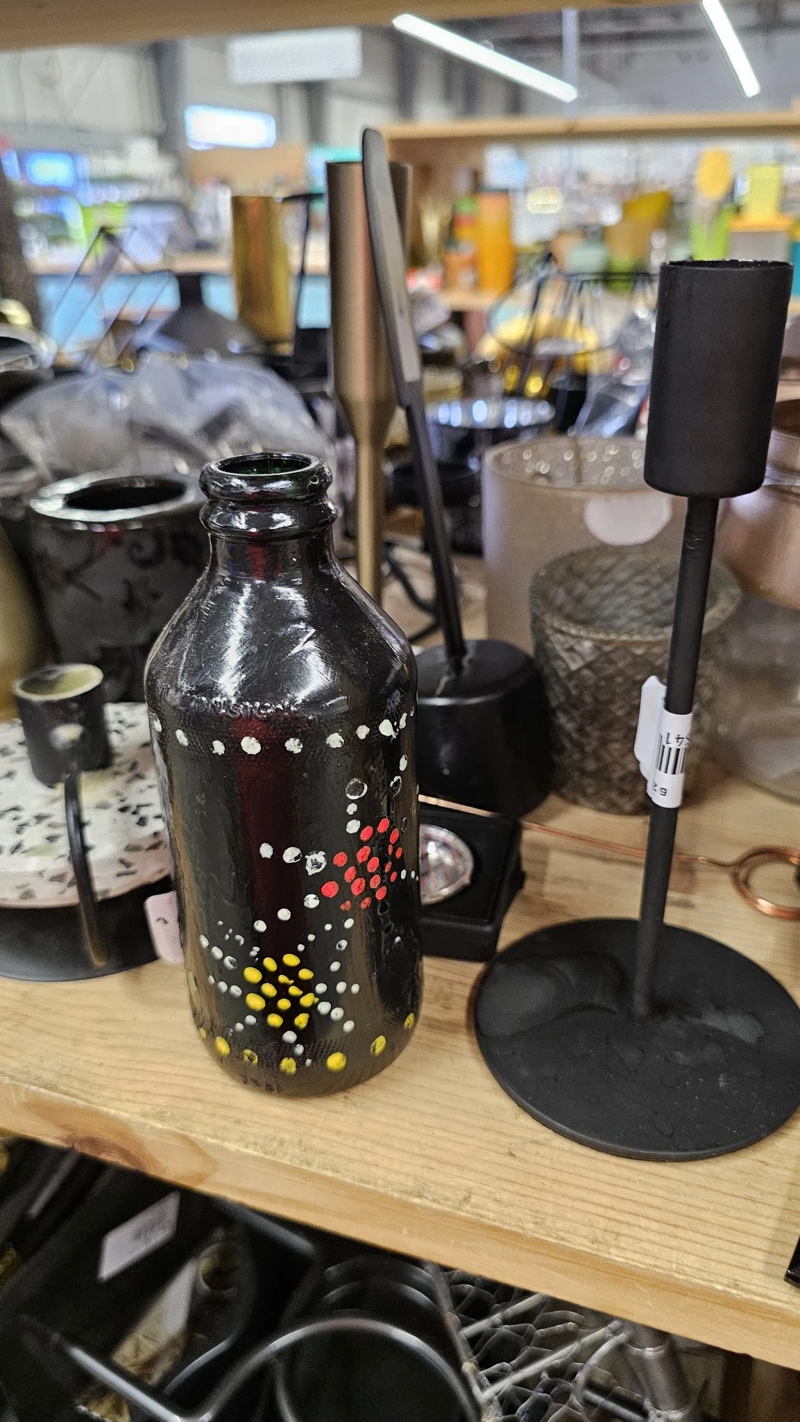 Zwarte glazen fles met decoratief patroon van gekleurde stippen