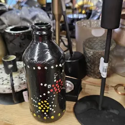 Zwarte glazen fles met decoratief patroon van gekleurde stippen