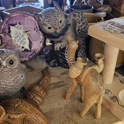 Houten beeldjes en decoratieve uilen op een tafel in de winkel