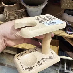 Houten speelgoedstaander met gat voor bal, voorzien van decoratieve brandwerk, wordt in hand gehouden