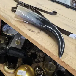 Close-up van een zwart glanzend decoratief object met golvende vormen op houten tafel